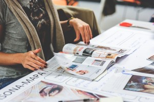 A woman looking at various printed materials spread out on a table.
