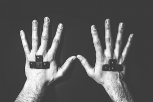 A black and white photo of the backs of a man's hands, with computer keys commonly used by each hand in online gaming controls.