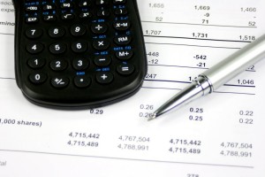 A calculator and pen on top of business financial documents.