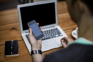 A man using a laptop and smartphone at the same time.