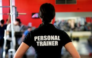 A woman in a gym wearing a Personal Trainer t-shirt.