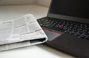 A newspaper and a laptop computer.