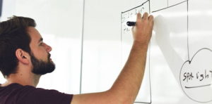 man sketching model on whiteboard