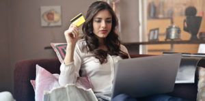 woman holding credit card in hand with laptop